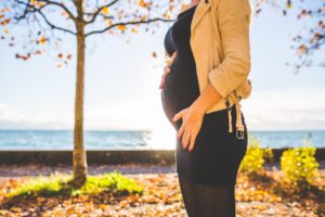 a healthy pregnant women standing by the beach